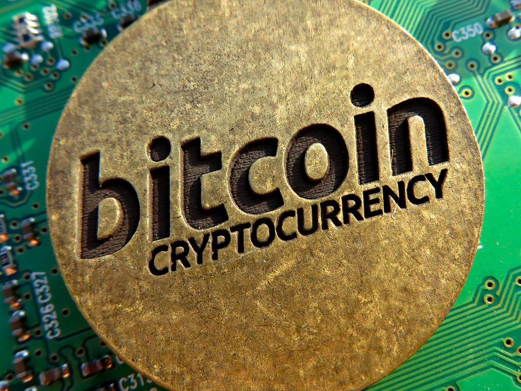 Pièces physiques de cryptomonnaie bitcoin posées sur une surface sombre