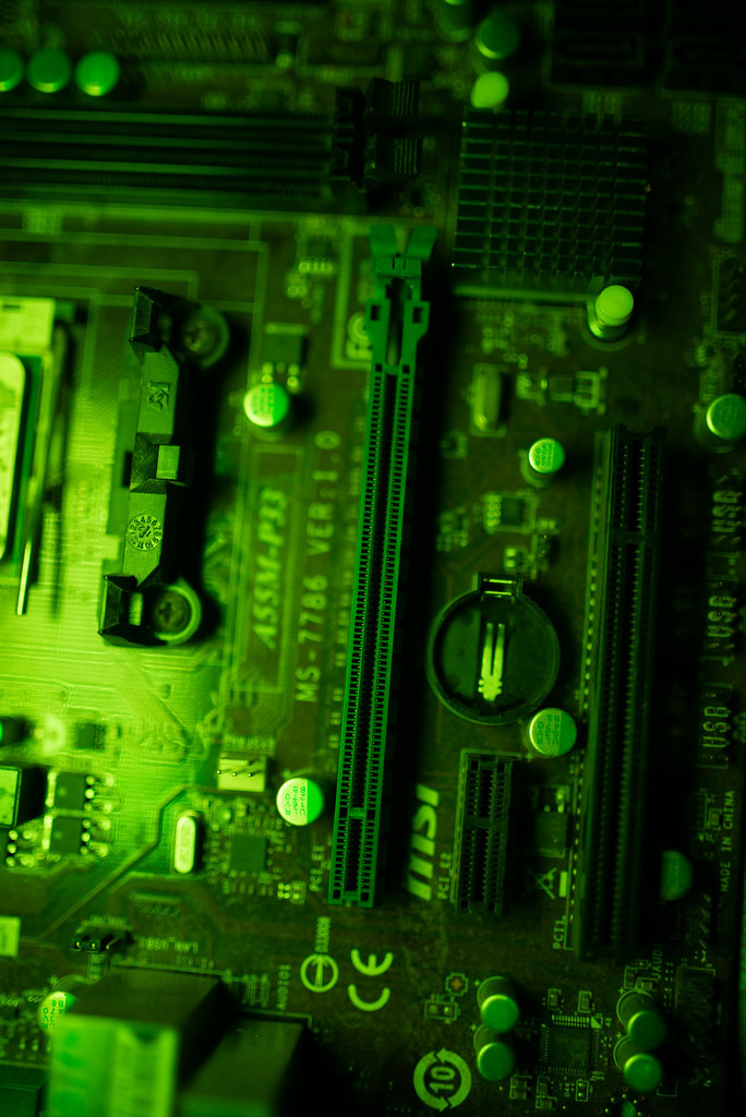 Gros plan sur une carte de circuit imprimé éclairée d'une lumière verte, illustrant les puces électroniques dédiées à l'intelligence artificielle