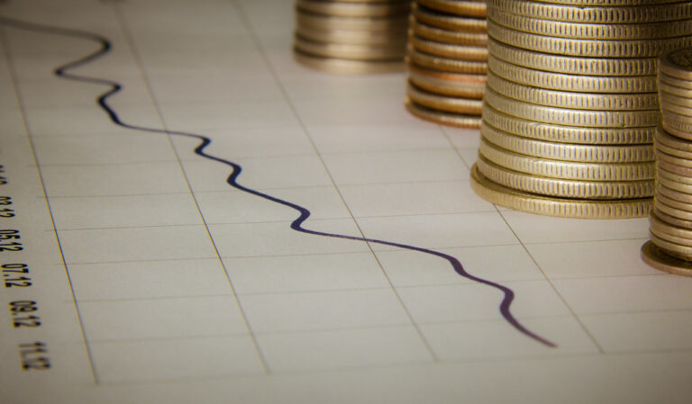 Pièces de monnaie empilées devant un graphique financier illustrant le trading