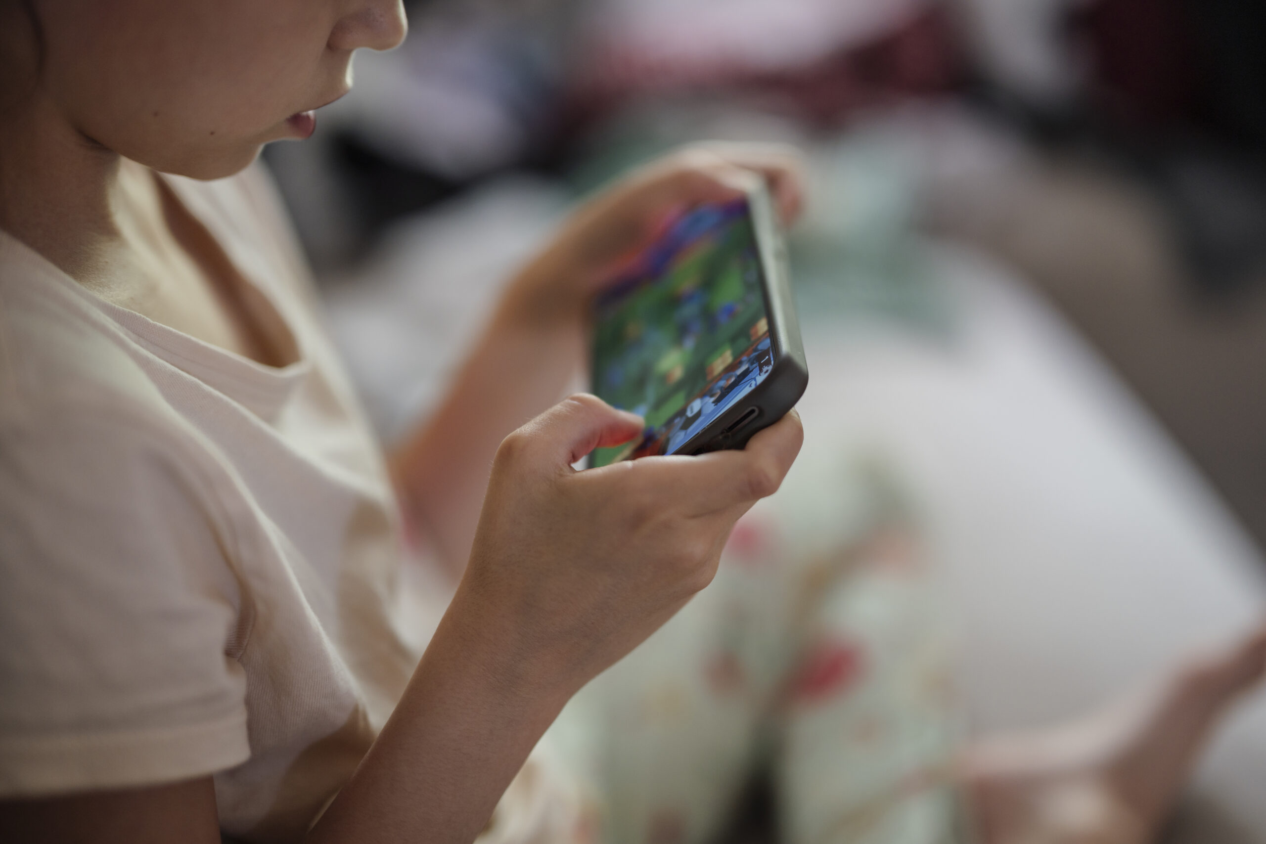Gros plan d'un enfant utilisant un smartphone, illustrant les enjeux de vérification d'âge en ligne dans l'Union européenne