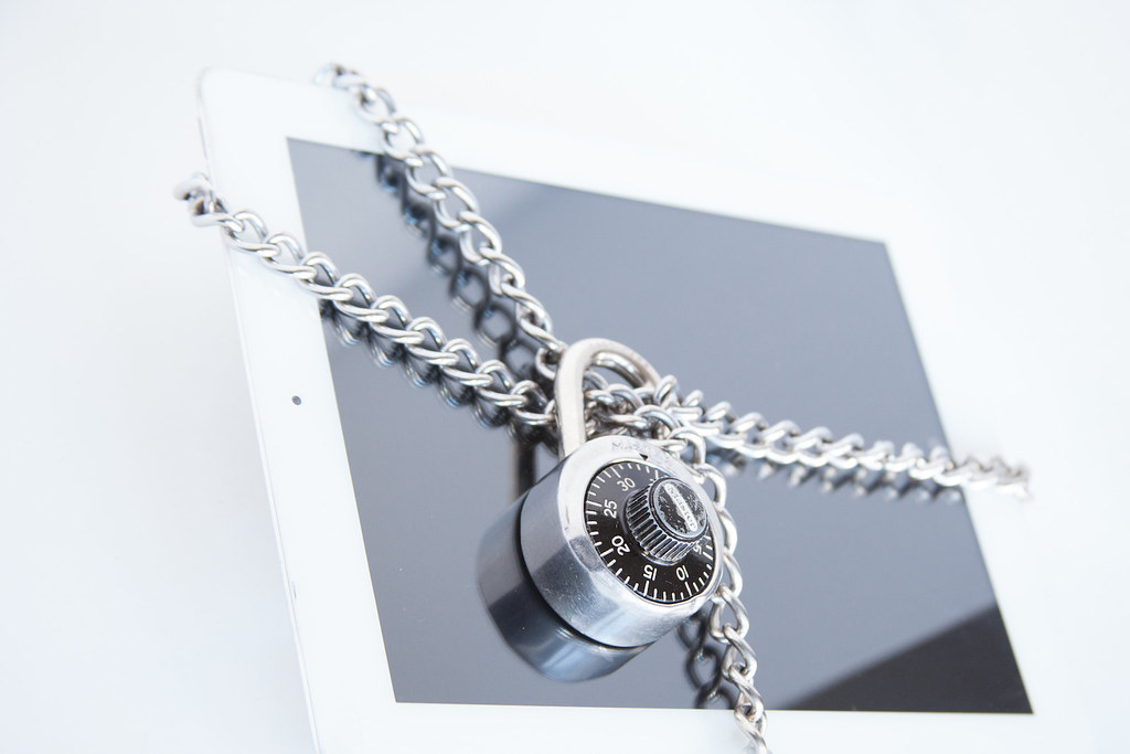 Tablette affichant un cadenas de cybersécurité posée sur un clavier d'ordinateur